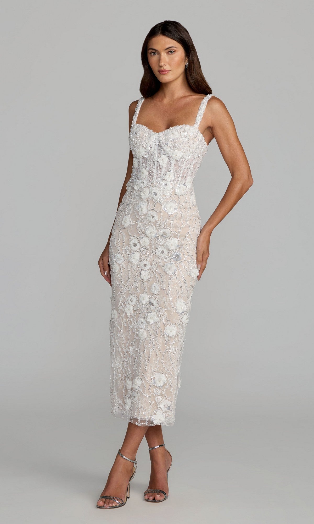 A woman wearing the Mac Duggal 21347 Midi Party Dress in Ivory Nude—featuring a fitted, sleeveless, mid-length silhouette with delicate floral lace embroidery—paired with silver high-heeled sandals, stands against a plain light gray background.